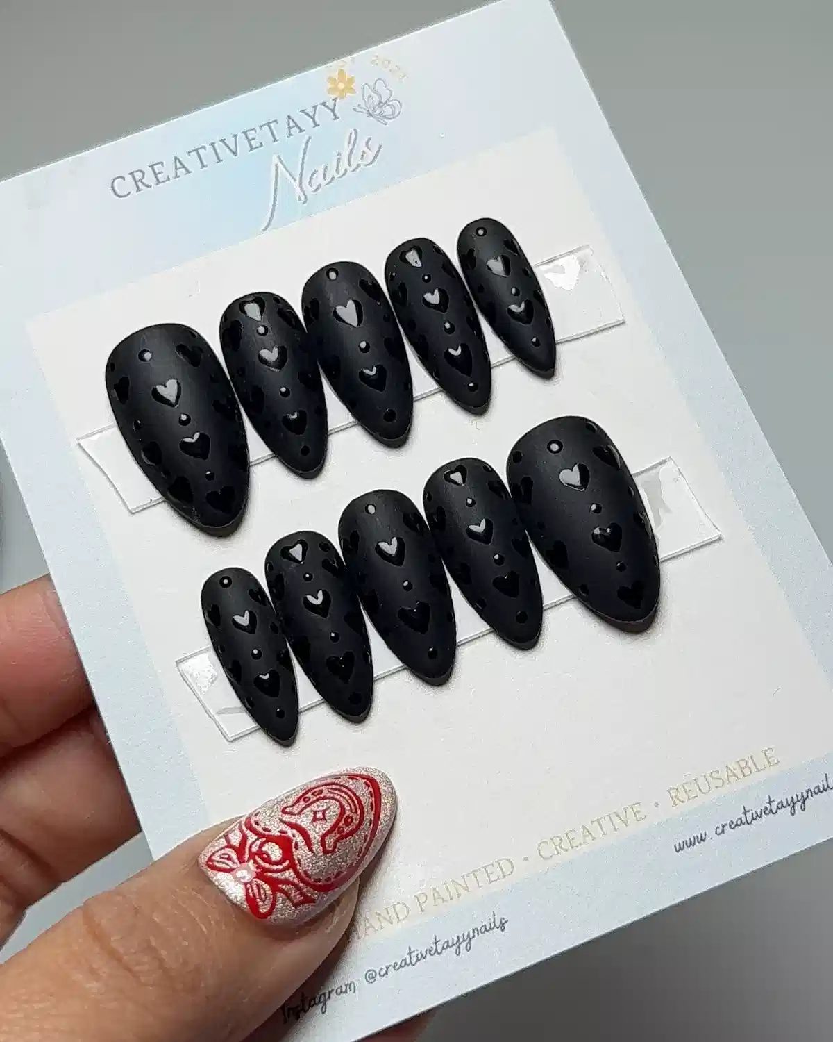 Matte black heart-cutout press-ons on branded display card