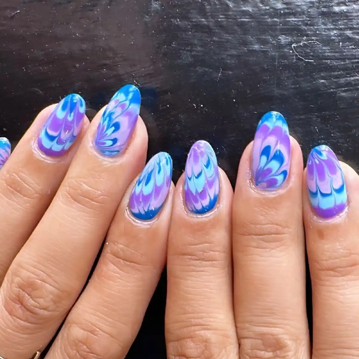 Blue-and-purple swirl marble across almond nails