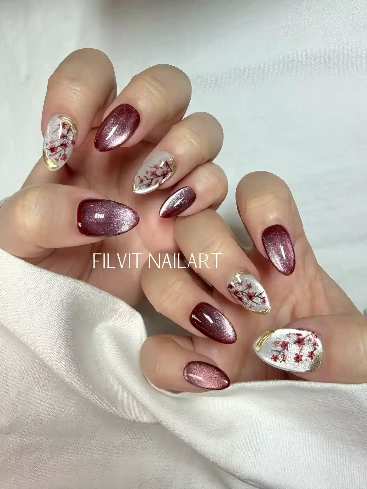 Burgundy shimmer with white floral accent nails and gold edging