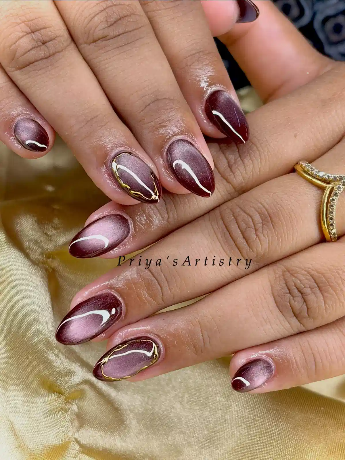 Burgundy-mauve cat-eye nails with gold outline accents