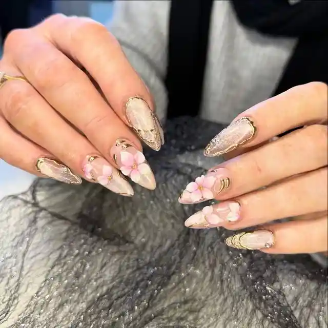 Nude stiletto nails with gold outlines and 3D flowers