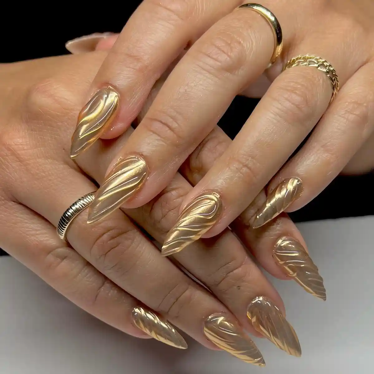 Full metallic-gold stiletto nails with raised wave texture