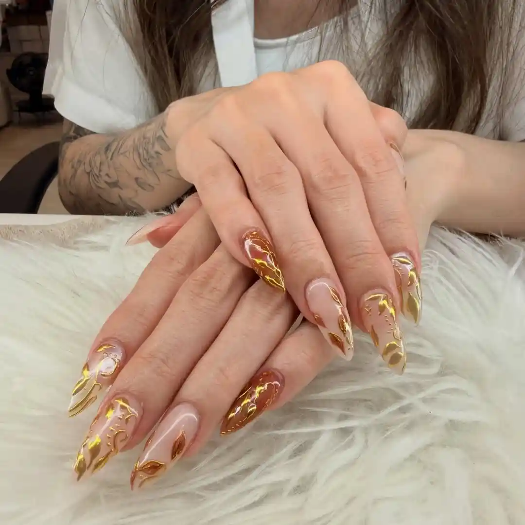 Swirling gold linework over nude and brown nails