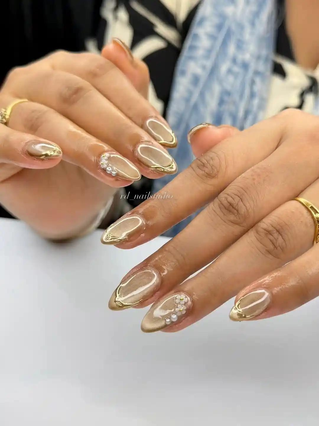 Nude almond nails with gold edging and pearl clusters