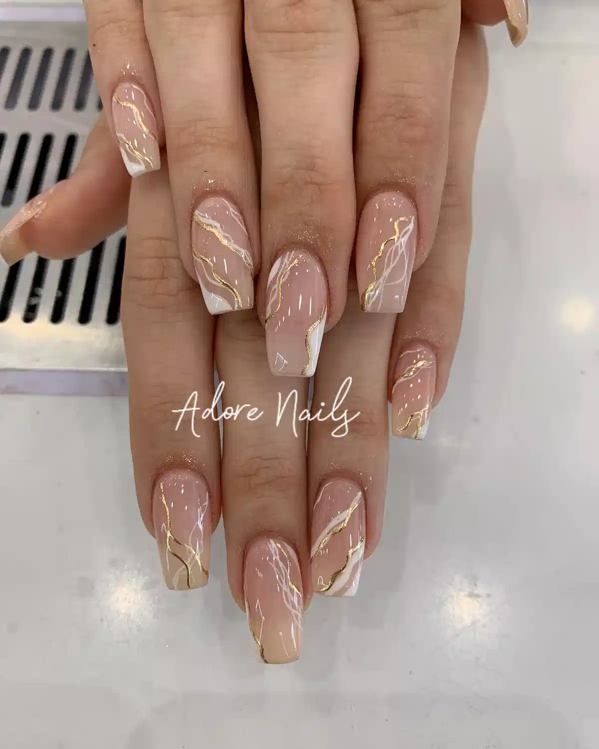 Nude square nails with white diagonal tips and gold waves