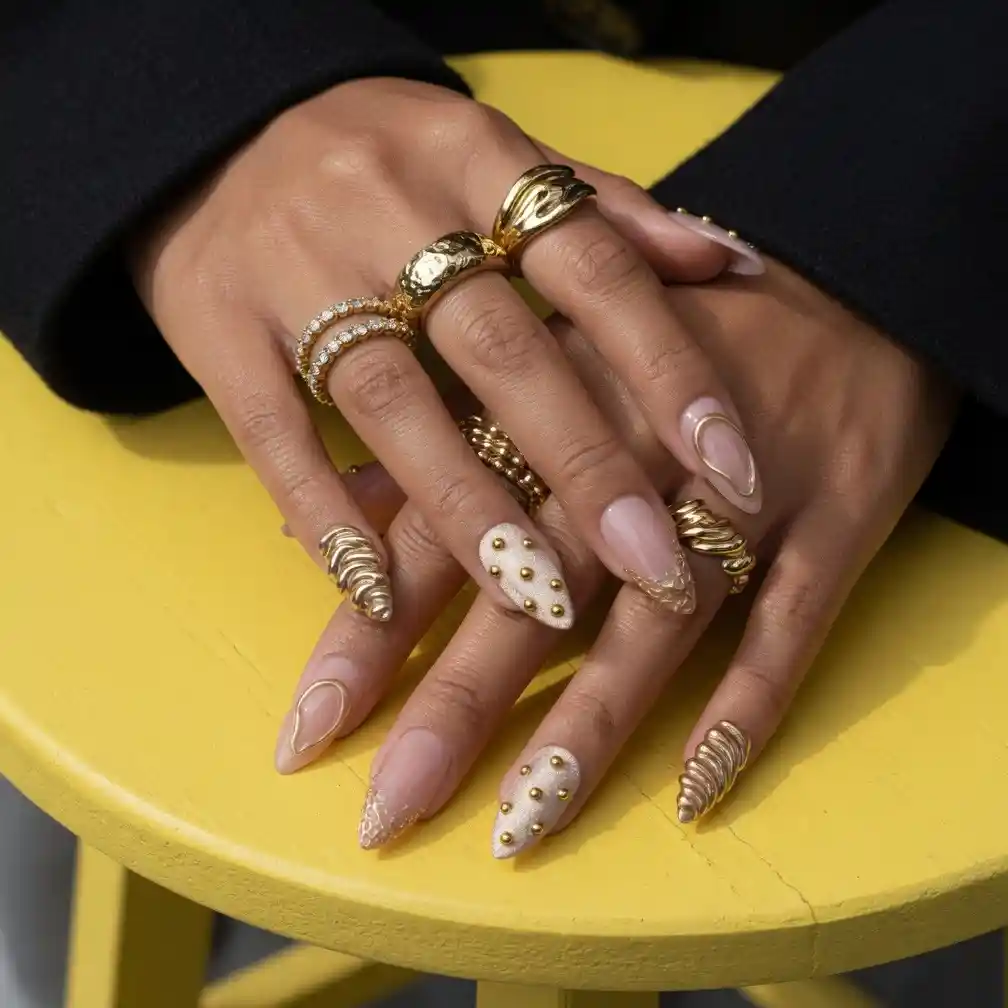 Gold-outlined nude nails with studs and sculpted spirals