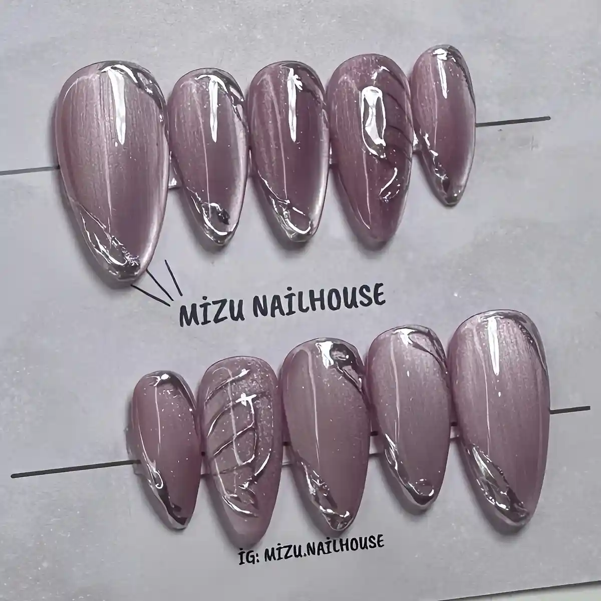 Glossy mauve-gray almond nails with subtle line accents
