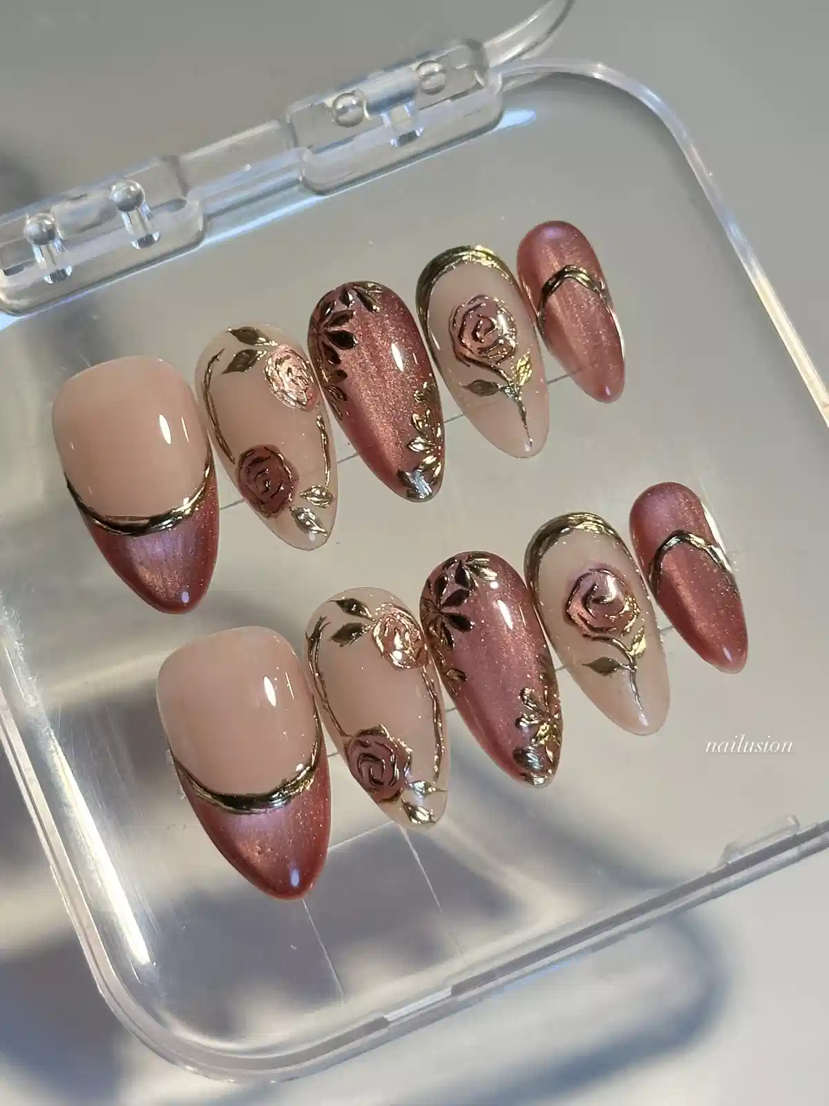 Nude and metallic rose nails with raised rose motifs and gold edging