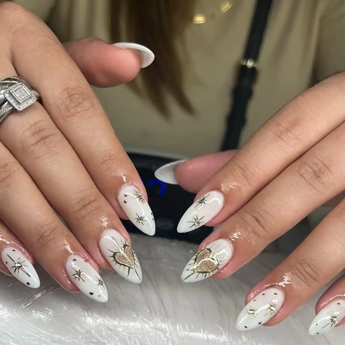 White nails with black starbursts and gold heart accents