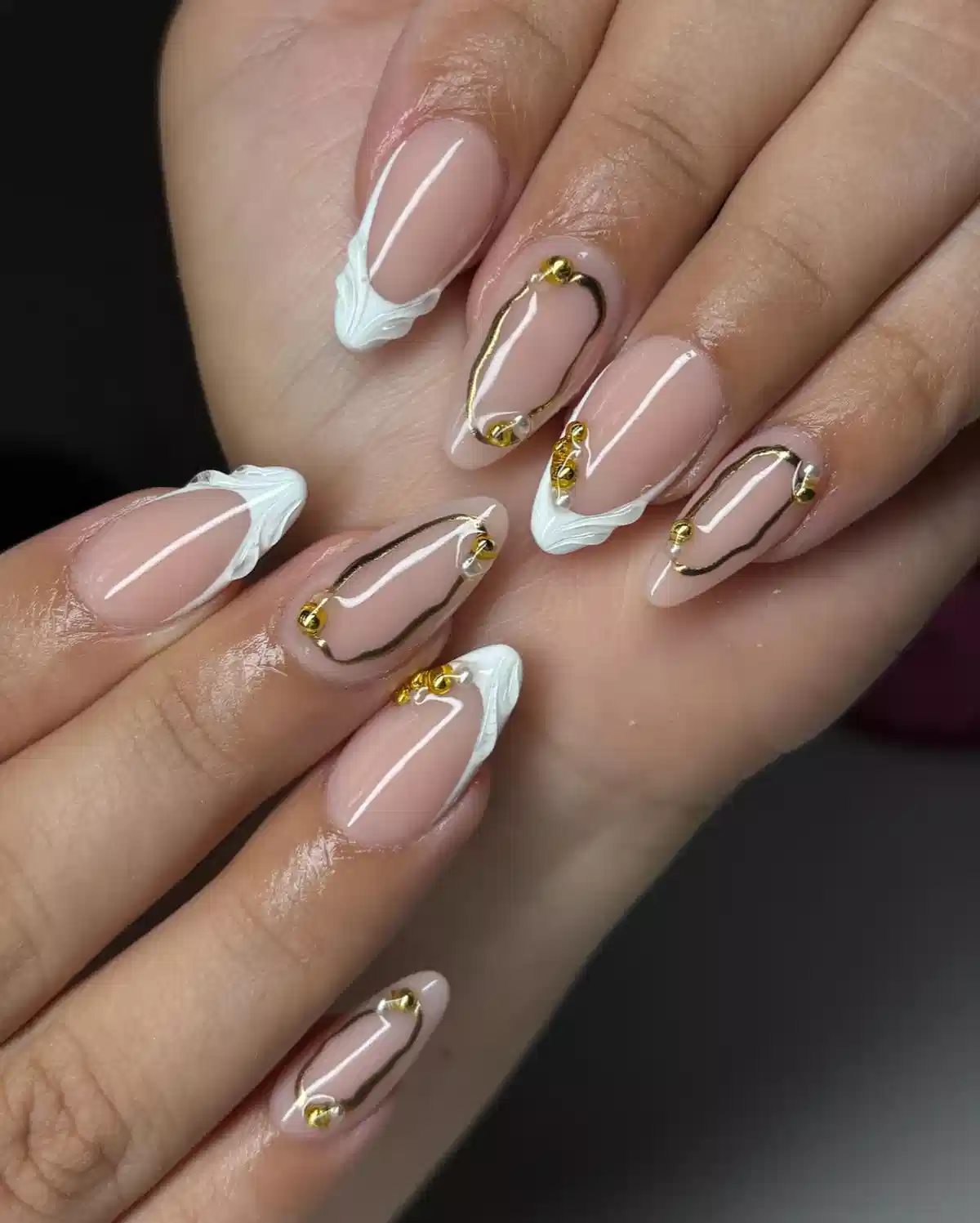 Nude almond nails with white sculpted tips and gold outlines
