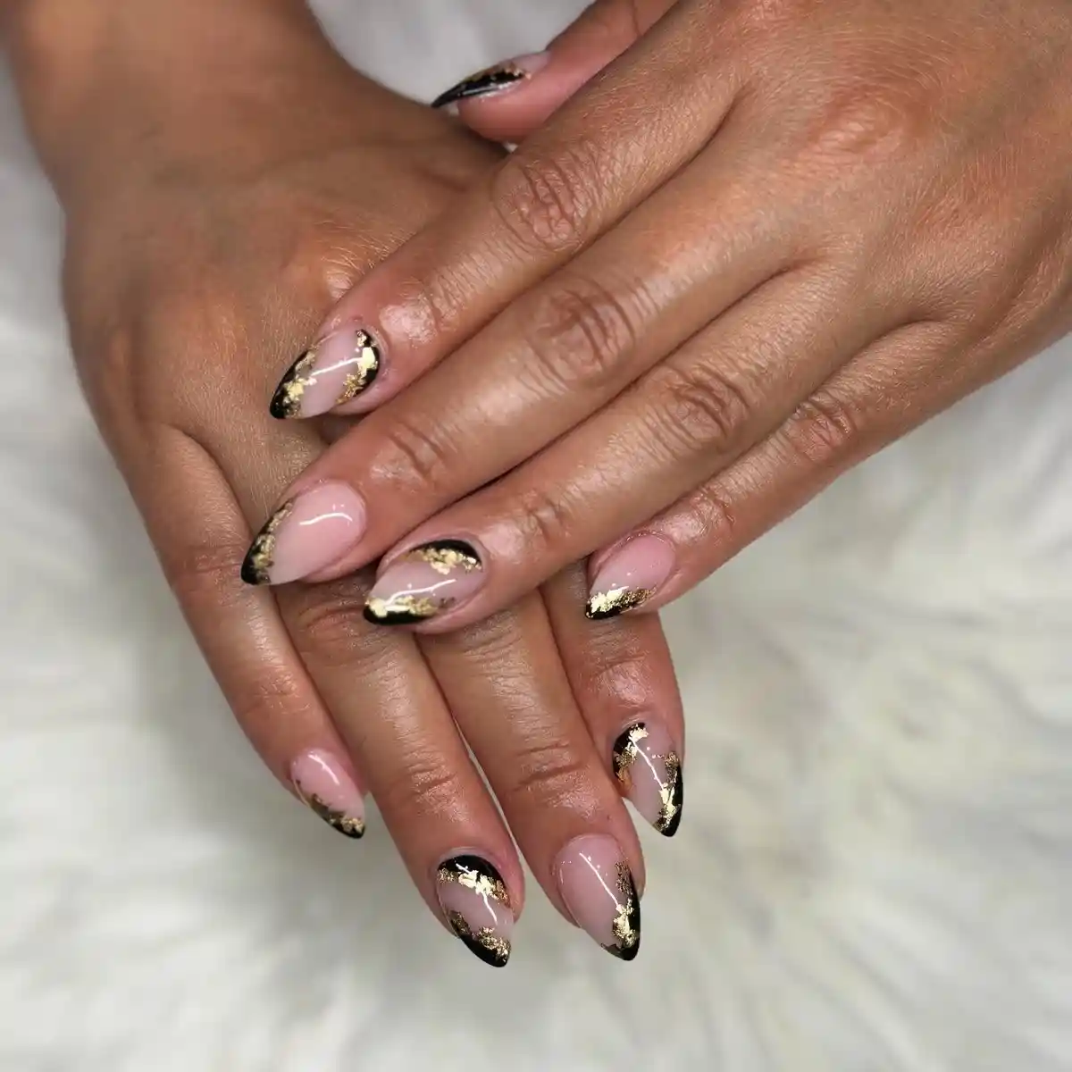 Nude nails with black tips and irregular gold foil-like accents