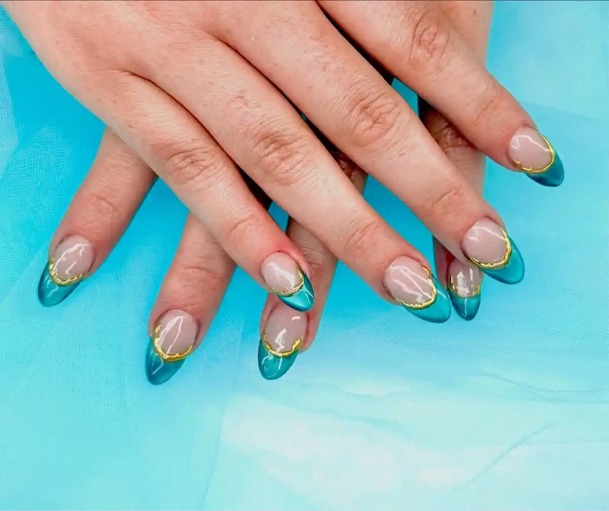 Nude base with teal French tips edged in gold