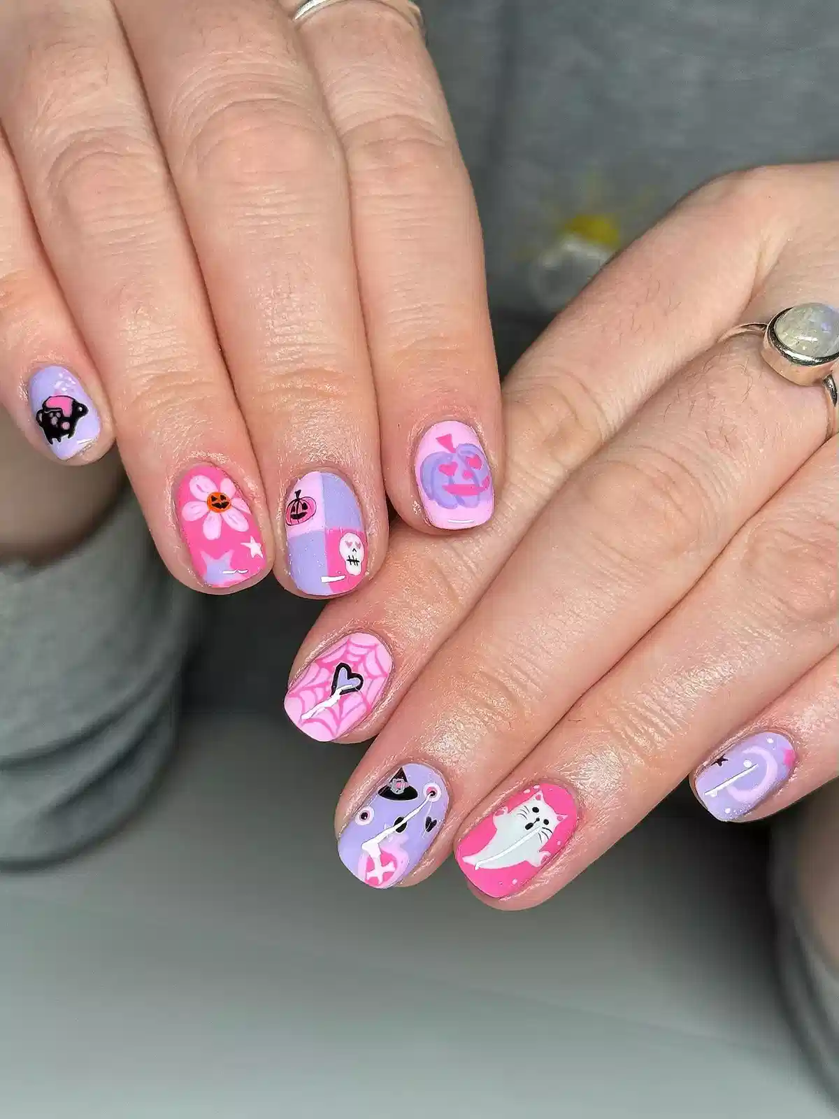Pink and lavender graphic nail art with cats and icons
