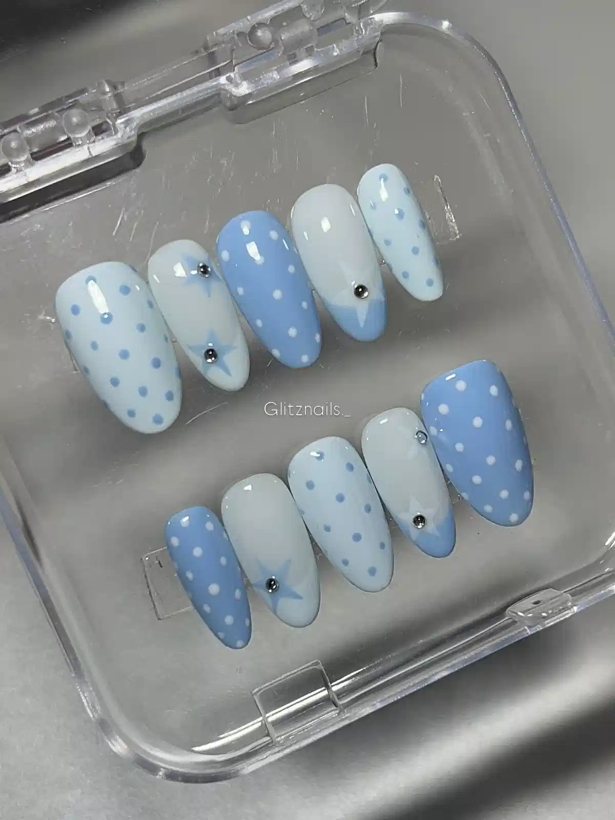 Light blue and white polka-dot press-ons with star accents in a case