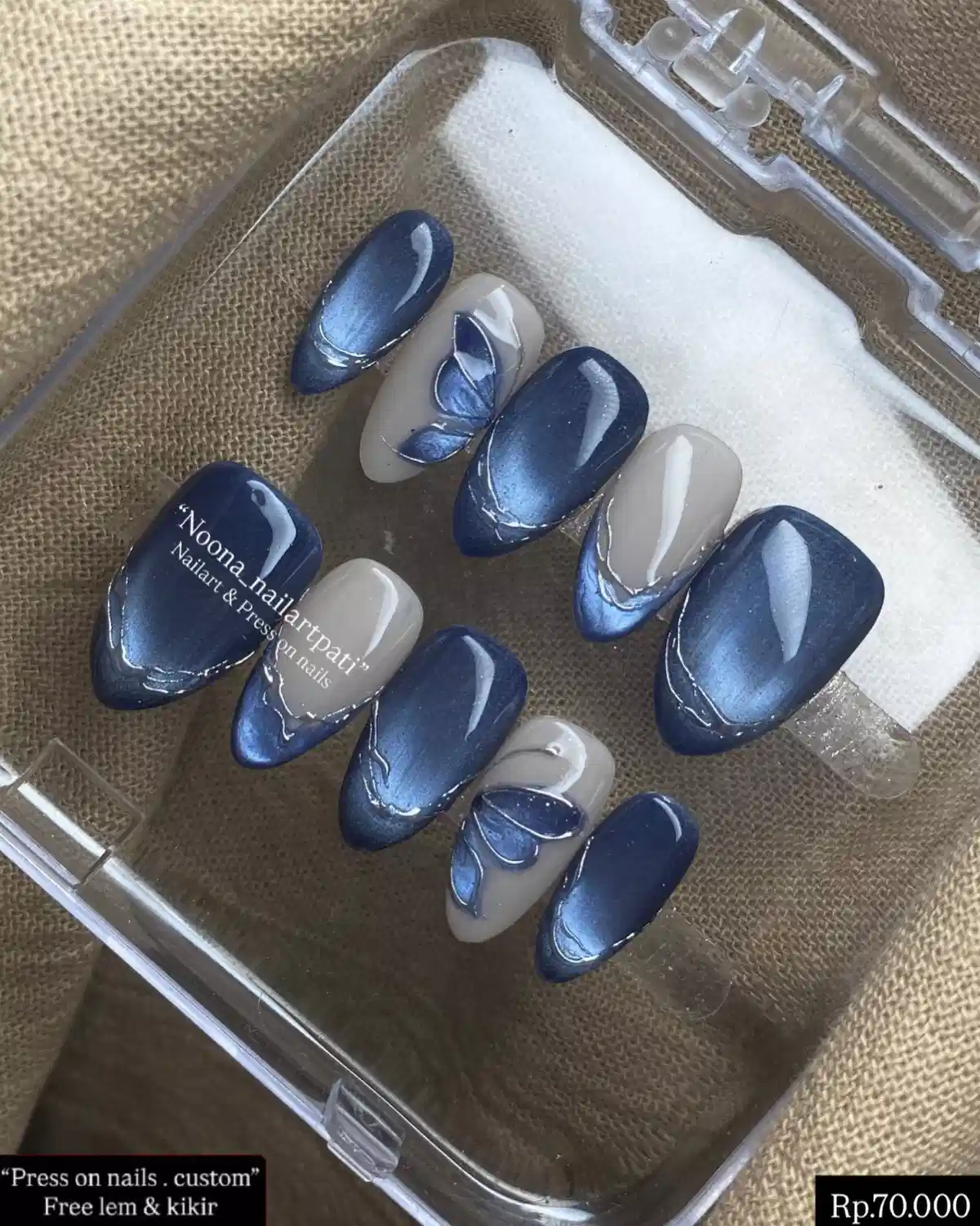 Navy and beige press-ons with metallic blue sheen and leaf accents