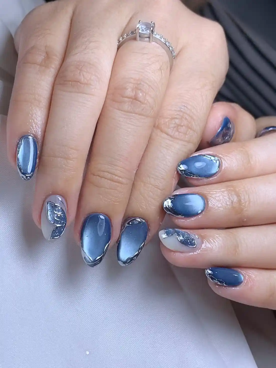 Blue-gray glossy nails with silver edging and leaf accents