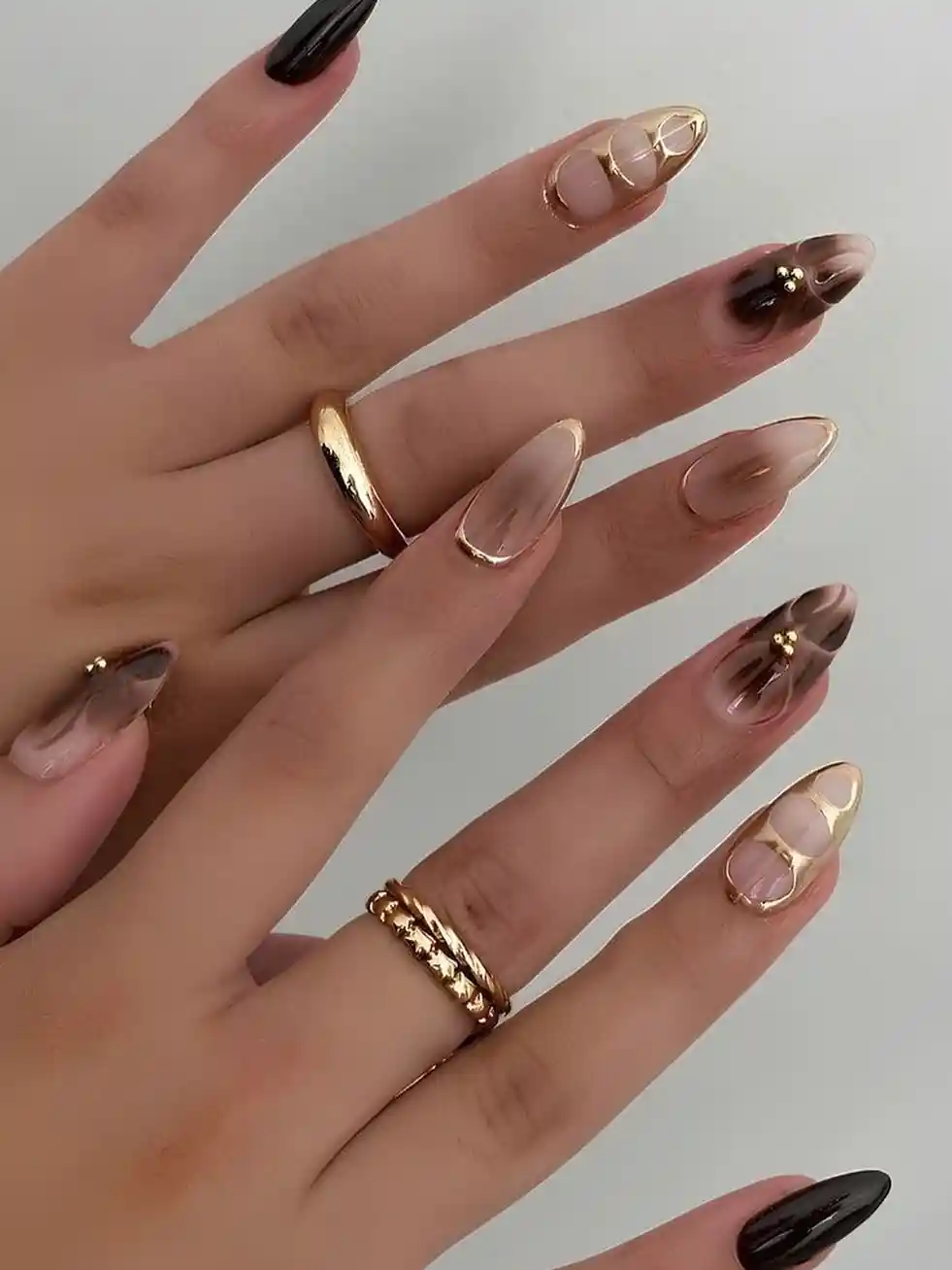 Nude-and-brown gradients with gold framing and a black accent nail