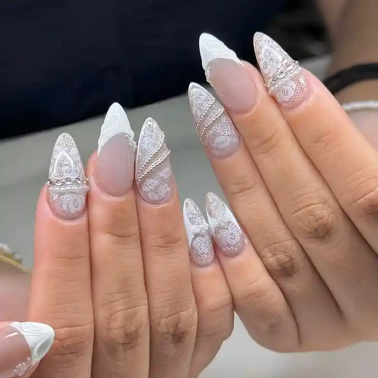 Pointed nude-and-white lace nails with detailed patterning
