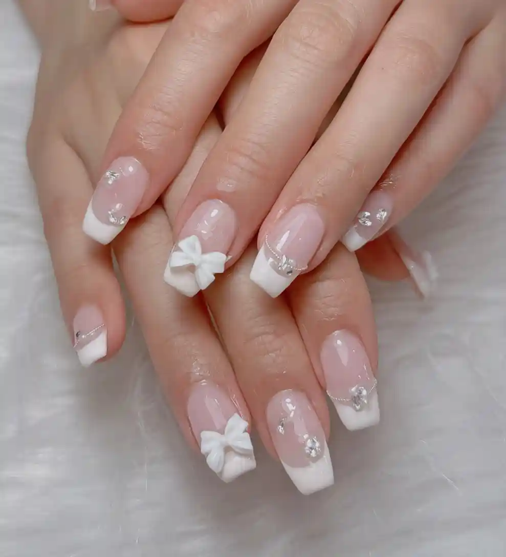 Square white French tips with 3D bows and rhinestone accents
