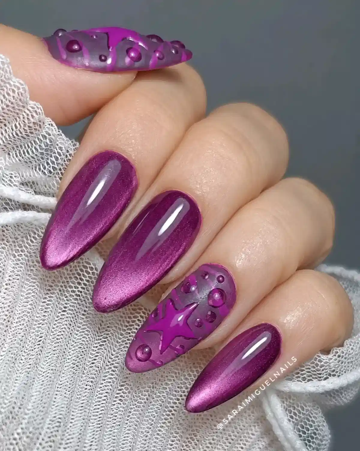 Magenta-purple cat-eye almond nails with 3D star accent
