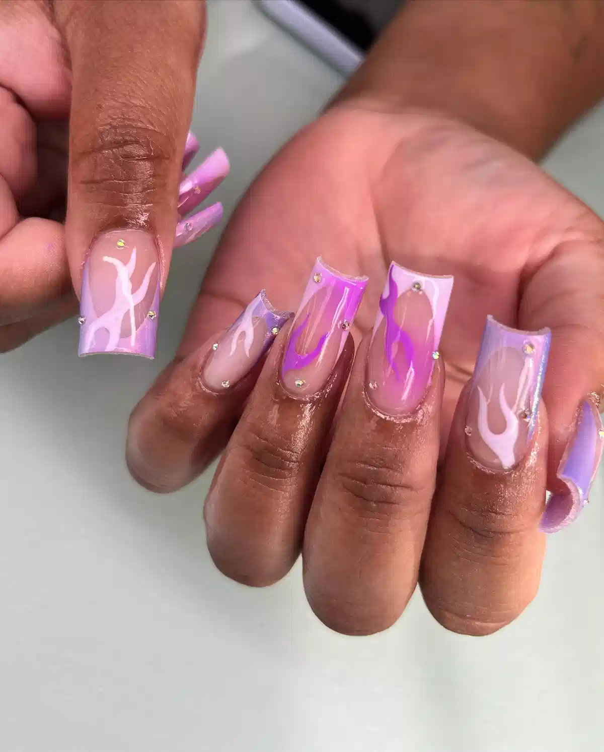 Purple flame design with rhinestone accents on long square nails