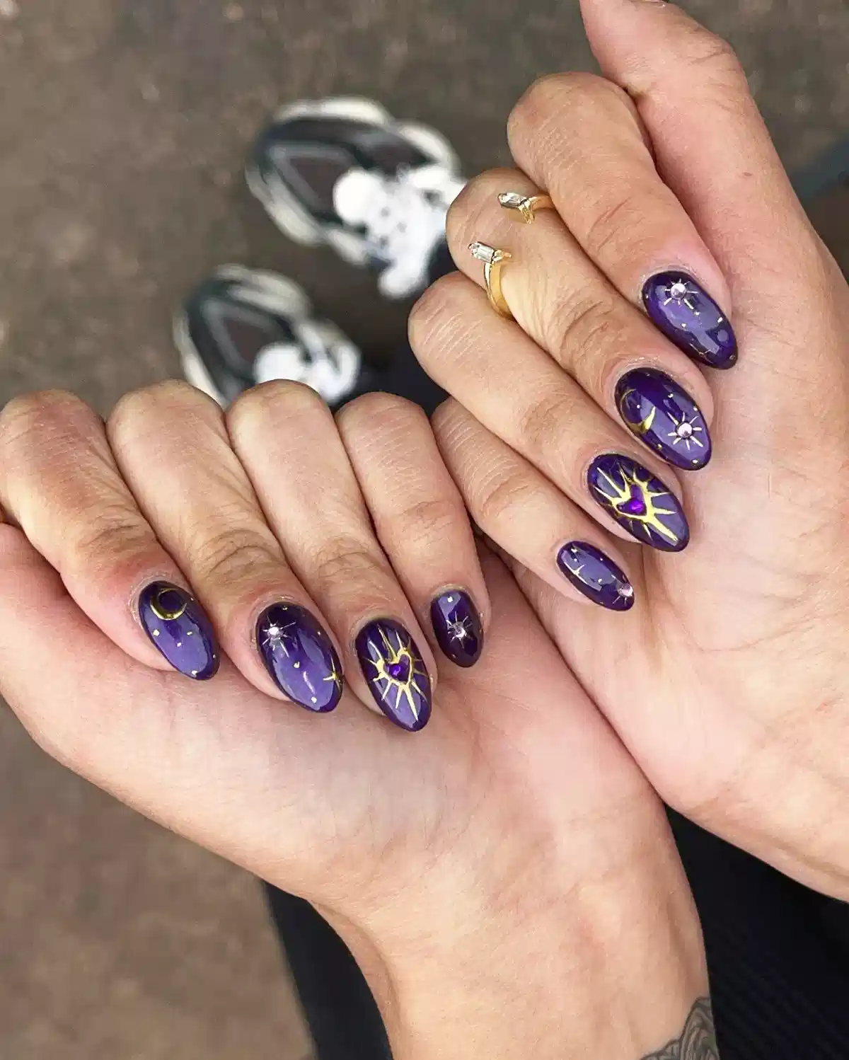 Deep purple nails with gold starbursts and a heart accent