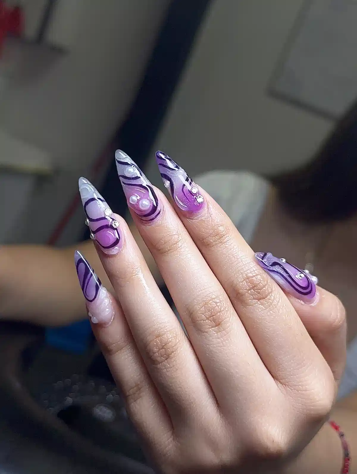 Purple swirl stiletto nails with pearls and rhinestones