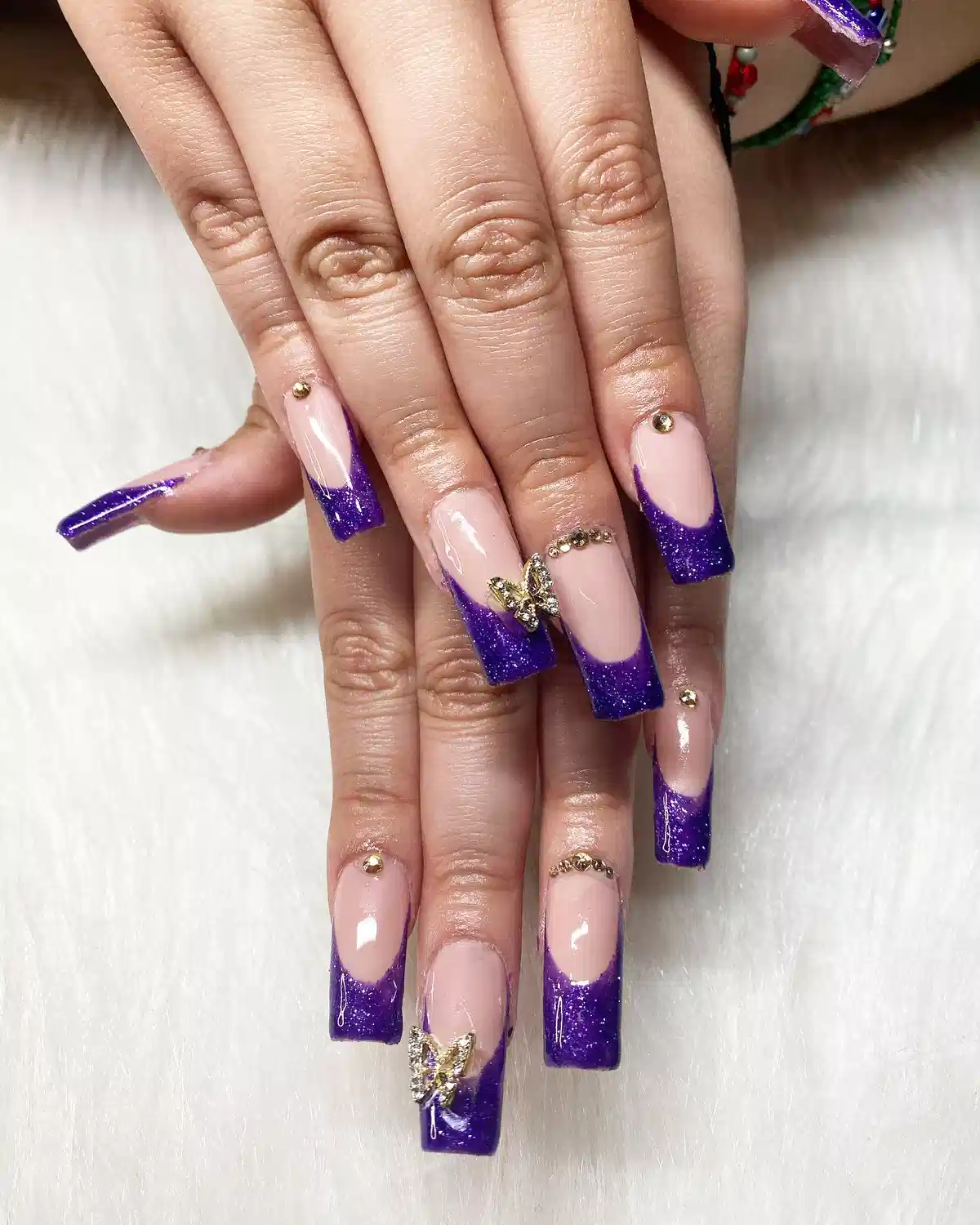 Deep purple glitter French tips with gold studs and butterfly accents