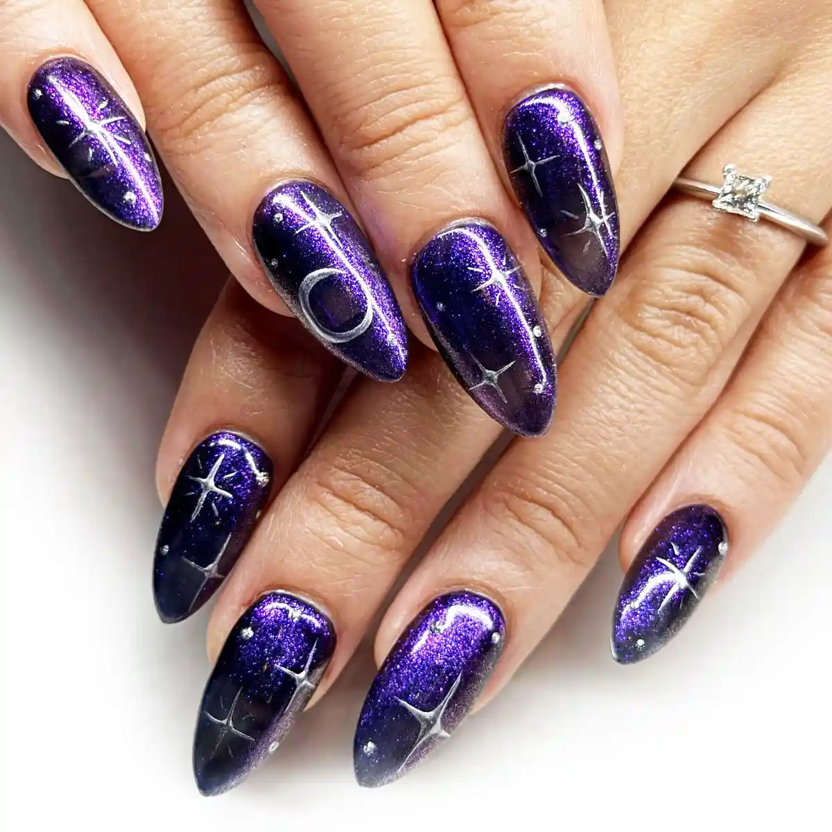 Dark purple celestial nails with starbursts and a crescent moon
