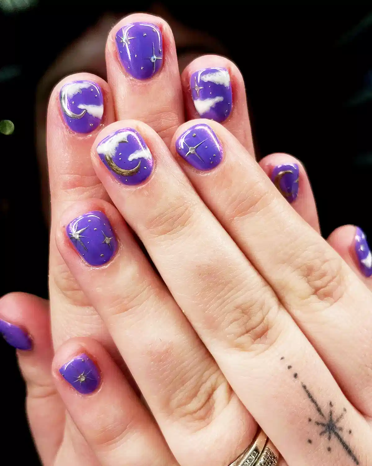 Purple celestial nails with moons, stars, and clouds