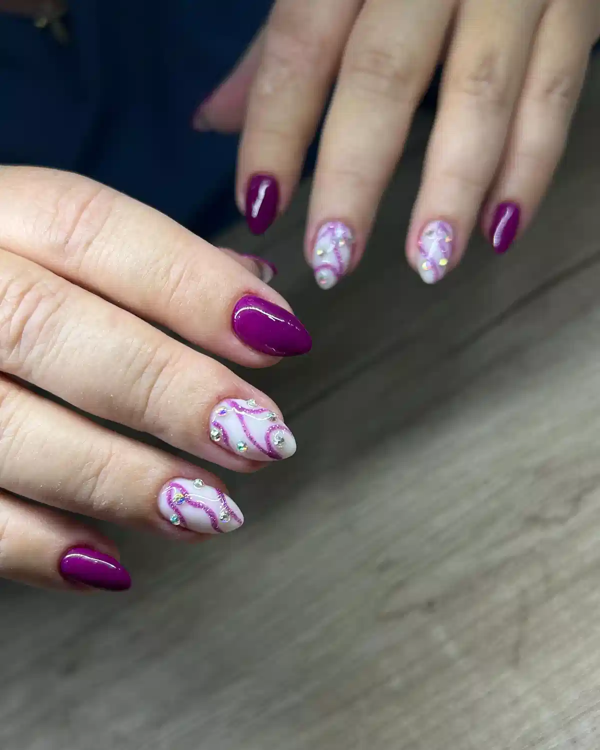 Deep purple solids with gem-accent swirl nails