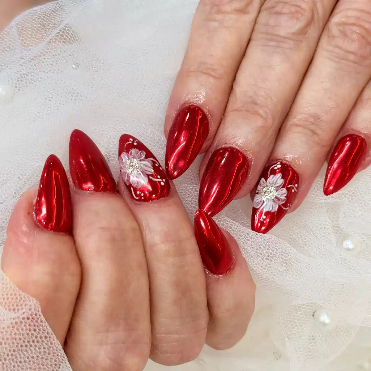 Metallic red almond nails with white floral accents