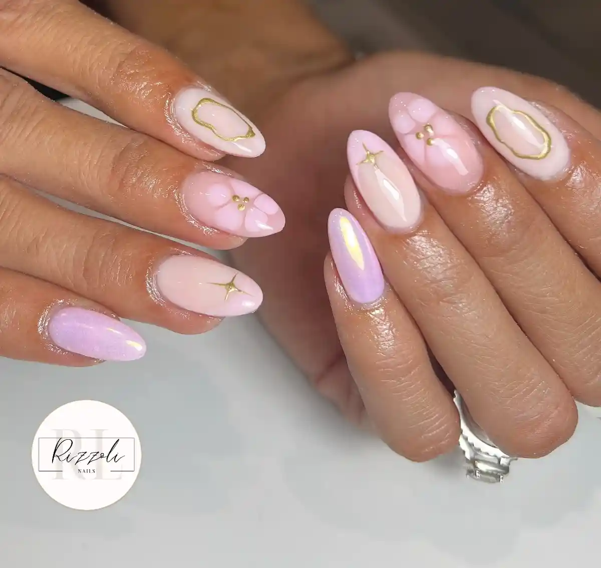 Pastel almond nails with gold frames, starbursts, and subtle floral accents