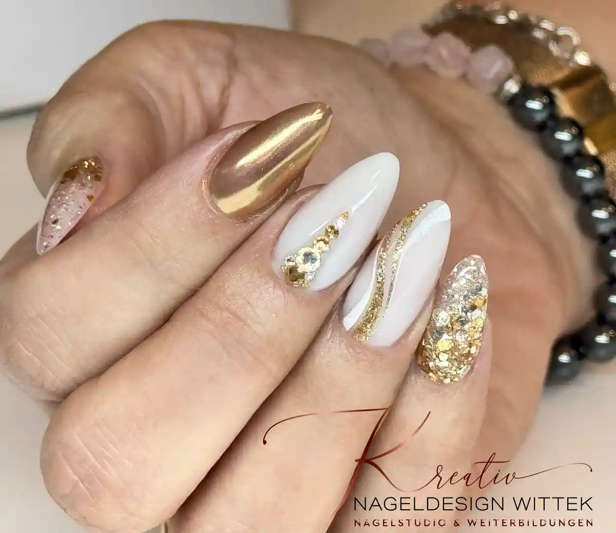 White nails with gold chrome, glitter, and rhinestone cluster