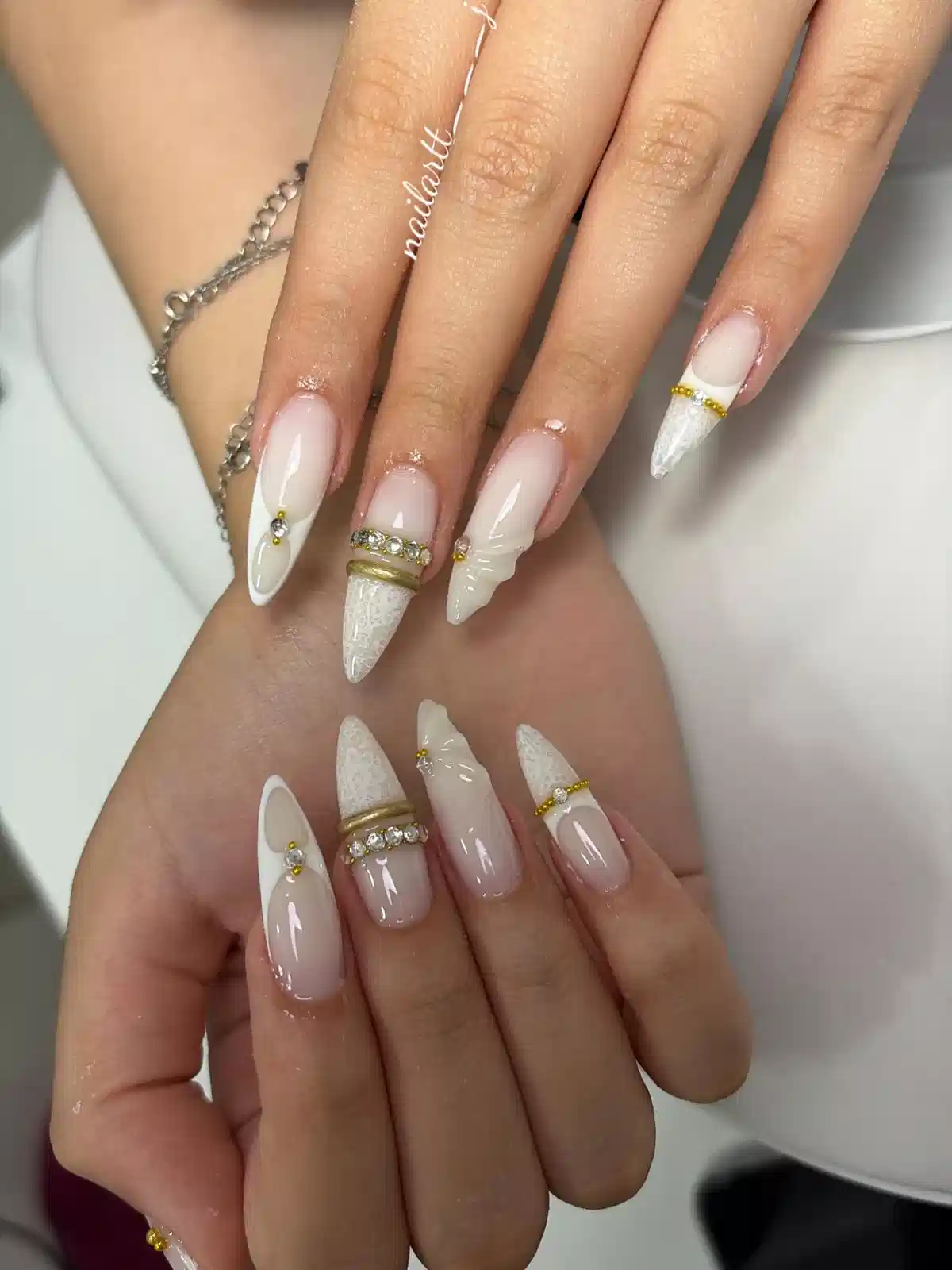 Stiletto nude-and-white tips with gold bands and stones