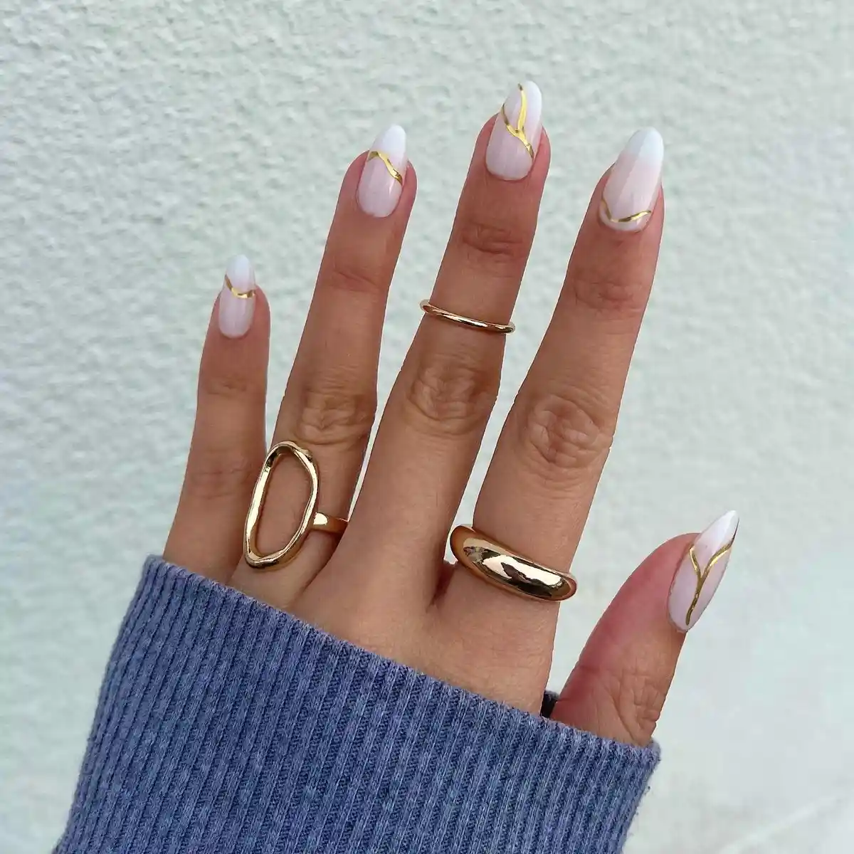 Soft ombré white nails with diagonal gold striping