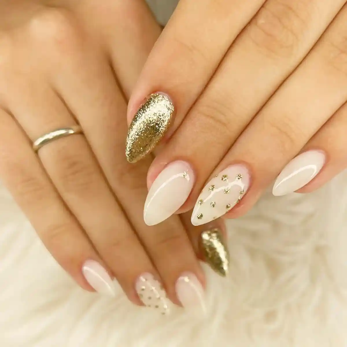 White almond nails with gold glitter and stud accents